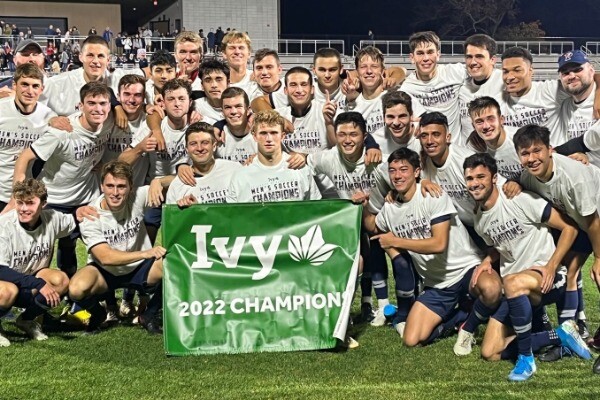 Following a win over Princeton in New Jersey, members of the men's soccer team pose on the field with the Ivy League championship banner.