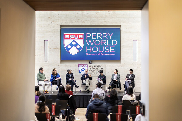 Seven China scholars sit on a stage in front of an audience at Perry World house