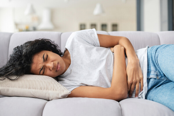 Person on  the couch clutching their stomach. 