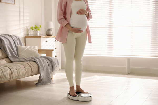 Pregnant person standing on a floor scale.