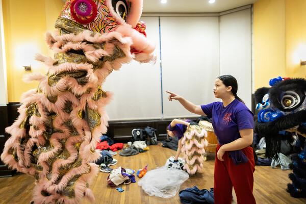 A lion dancer gives instruction to one of the Penn Lions. Inside the frilly, pink and gold lion costume are two Penn students 