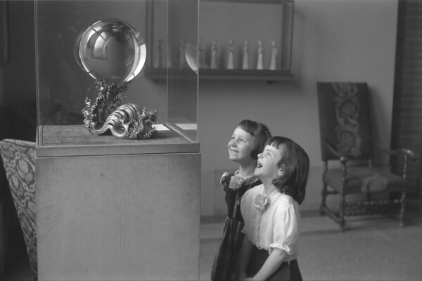 A historic, black-and-white image of two children gazing at the crystal ball 