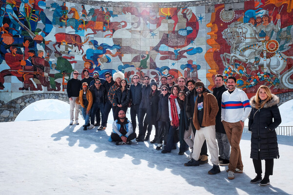 Group of people huddled together in front of a mural. 