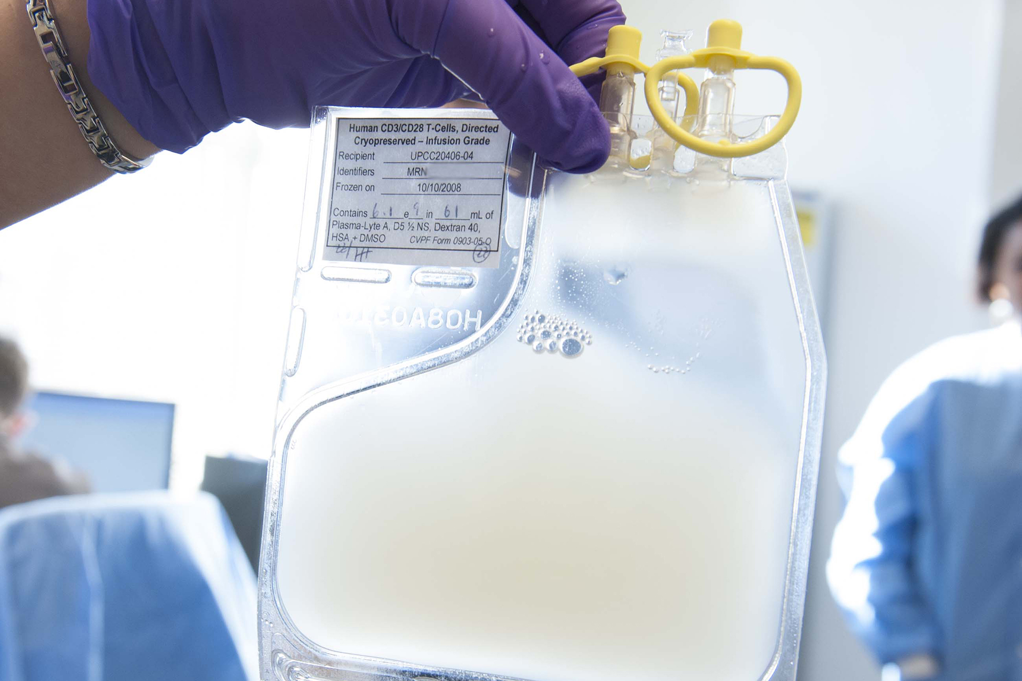 Person in gloves holding a medical bag of liquids. 