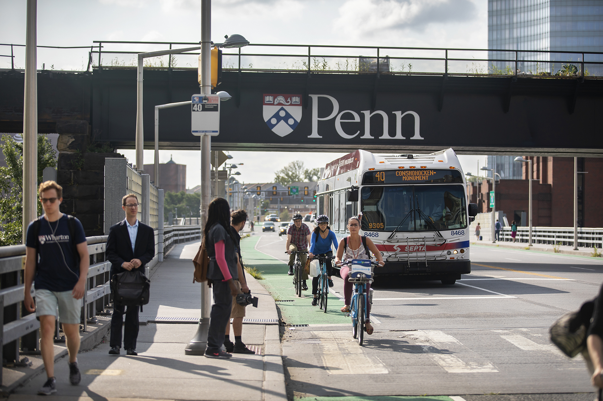 Pedestrians on the sidewalk, bikers in the bike lane, and a Septa bus in the street.