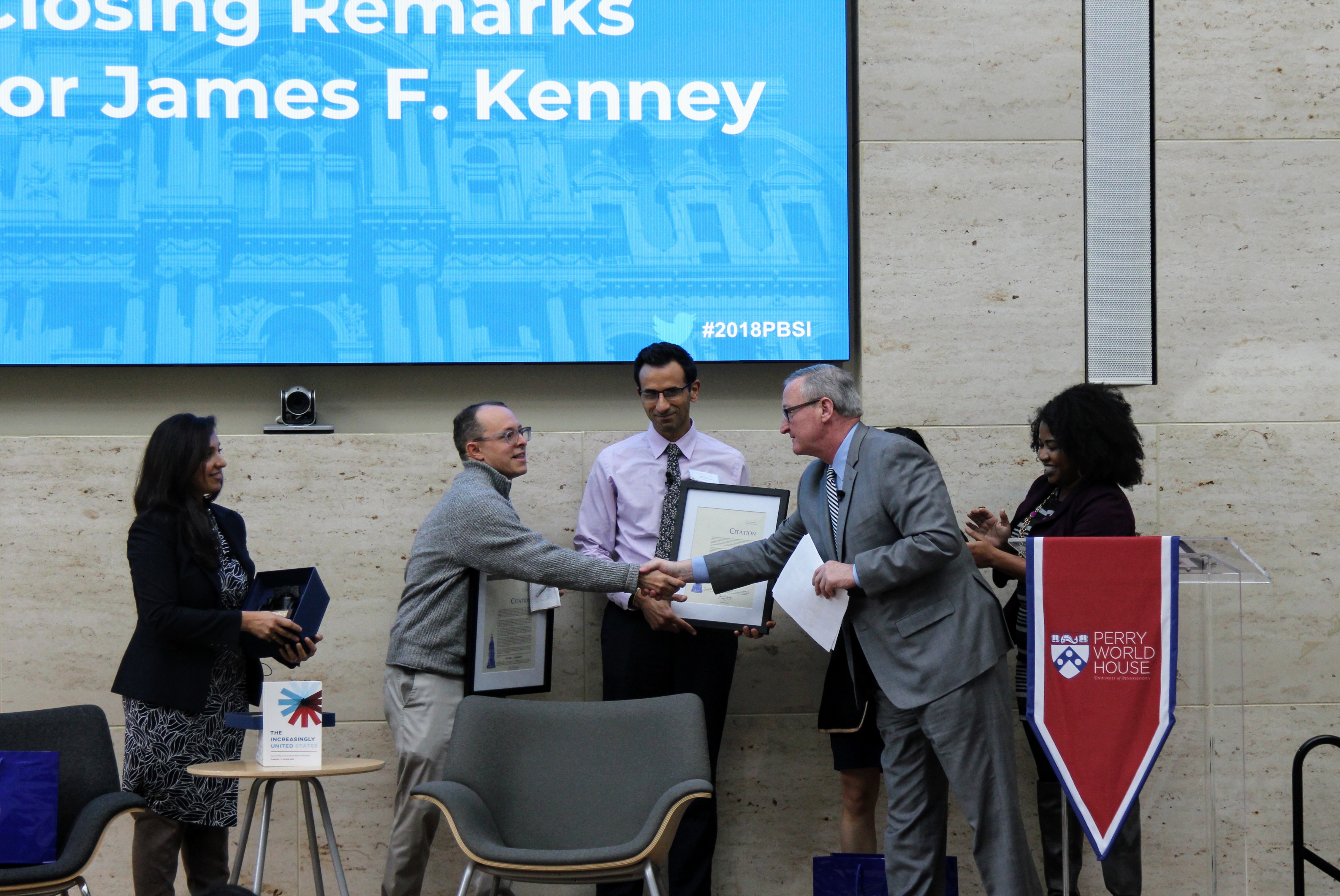 Mayor Kenney shakes hands with Daniel Hopkins on stage at Perry World House