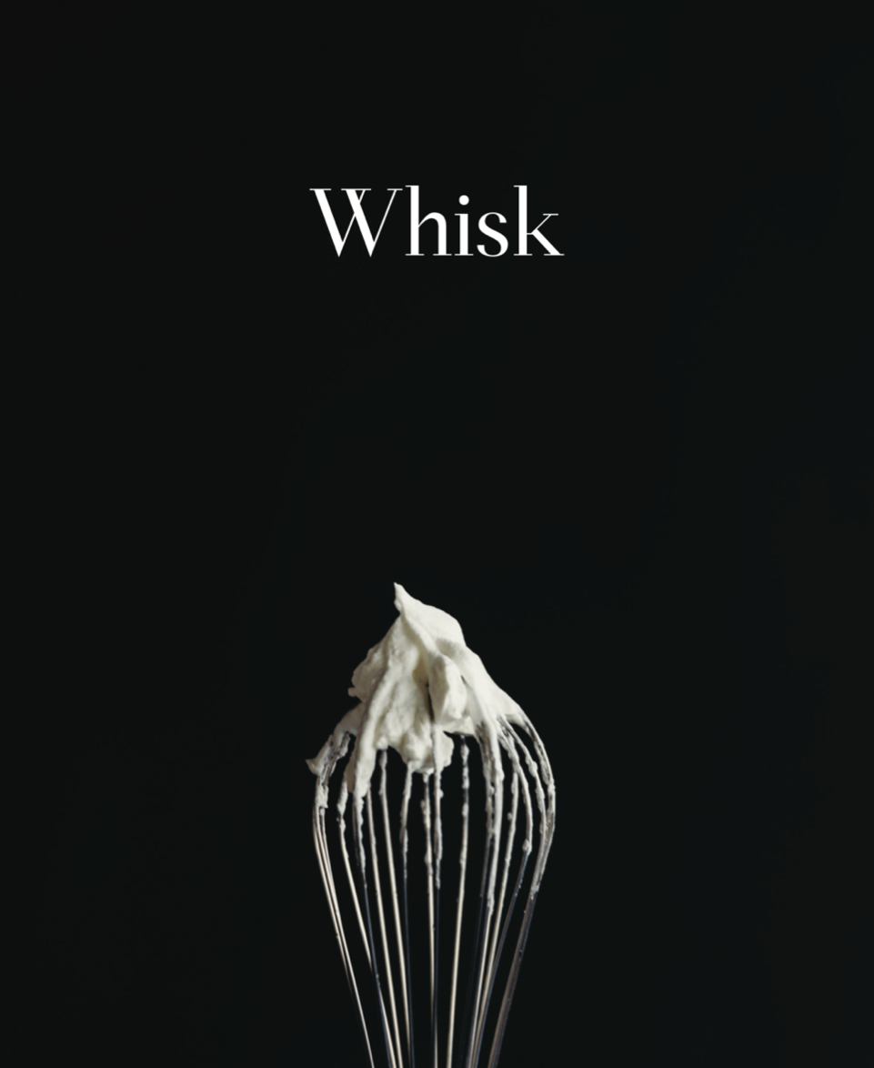 A whisk covered in a thick white batter in front of a black backdrop