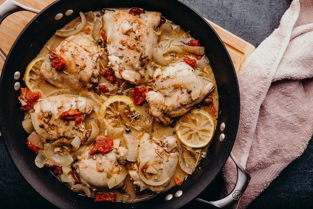 Chicken cacciatore in a large pot with a towel by its side