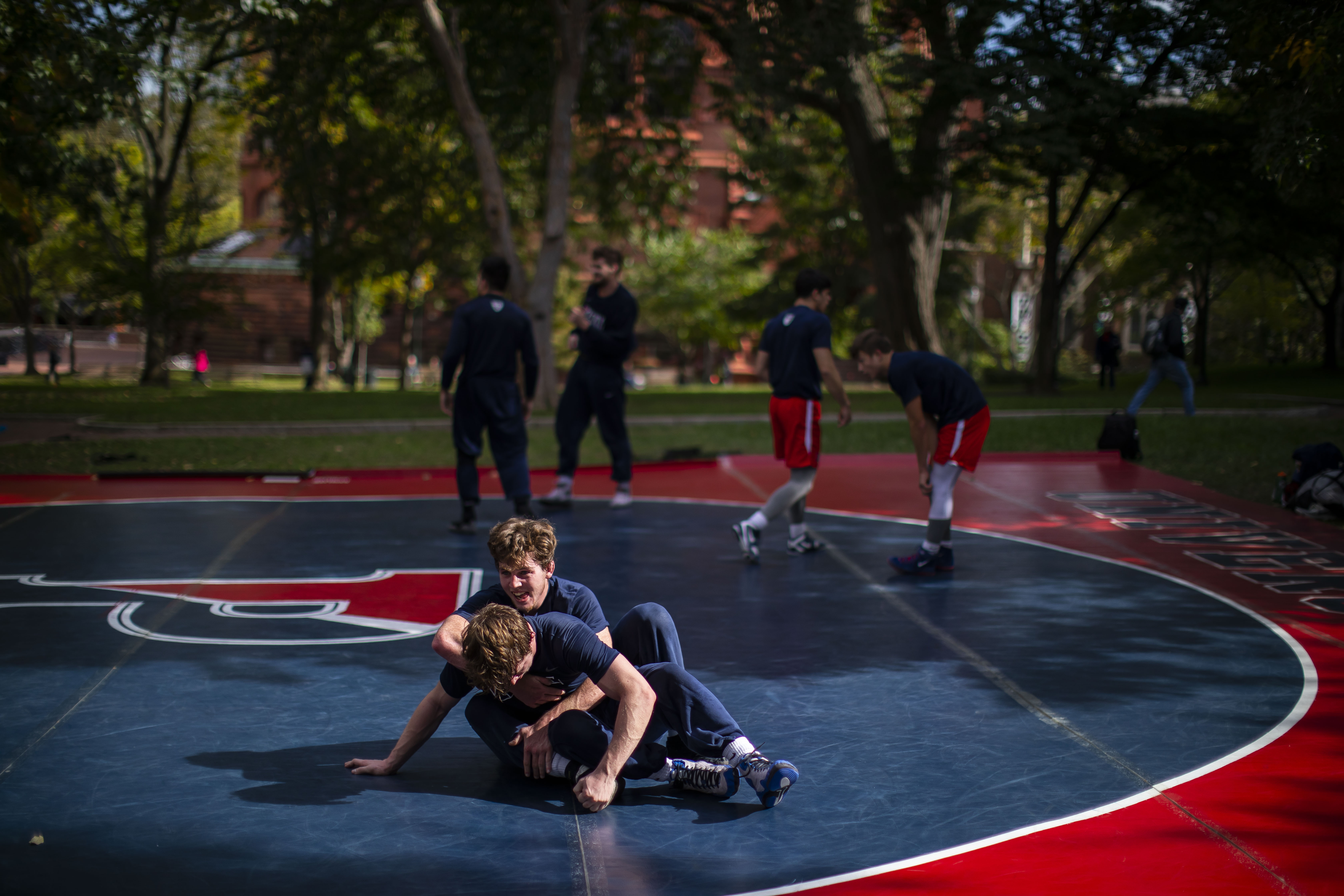 two-wrestlers-on-the-ground-during-outdoor-practice-with-trees-in-background
