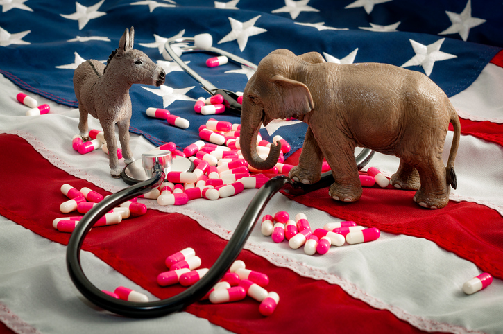 Elephant and donkey stand on american flag and peer across a stethoscope and pills at one another to indicate the prevalance of healtchare in the midterm election