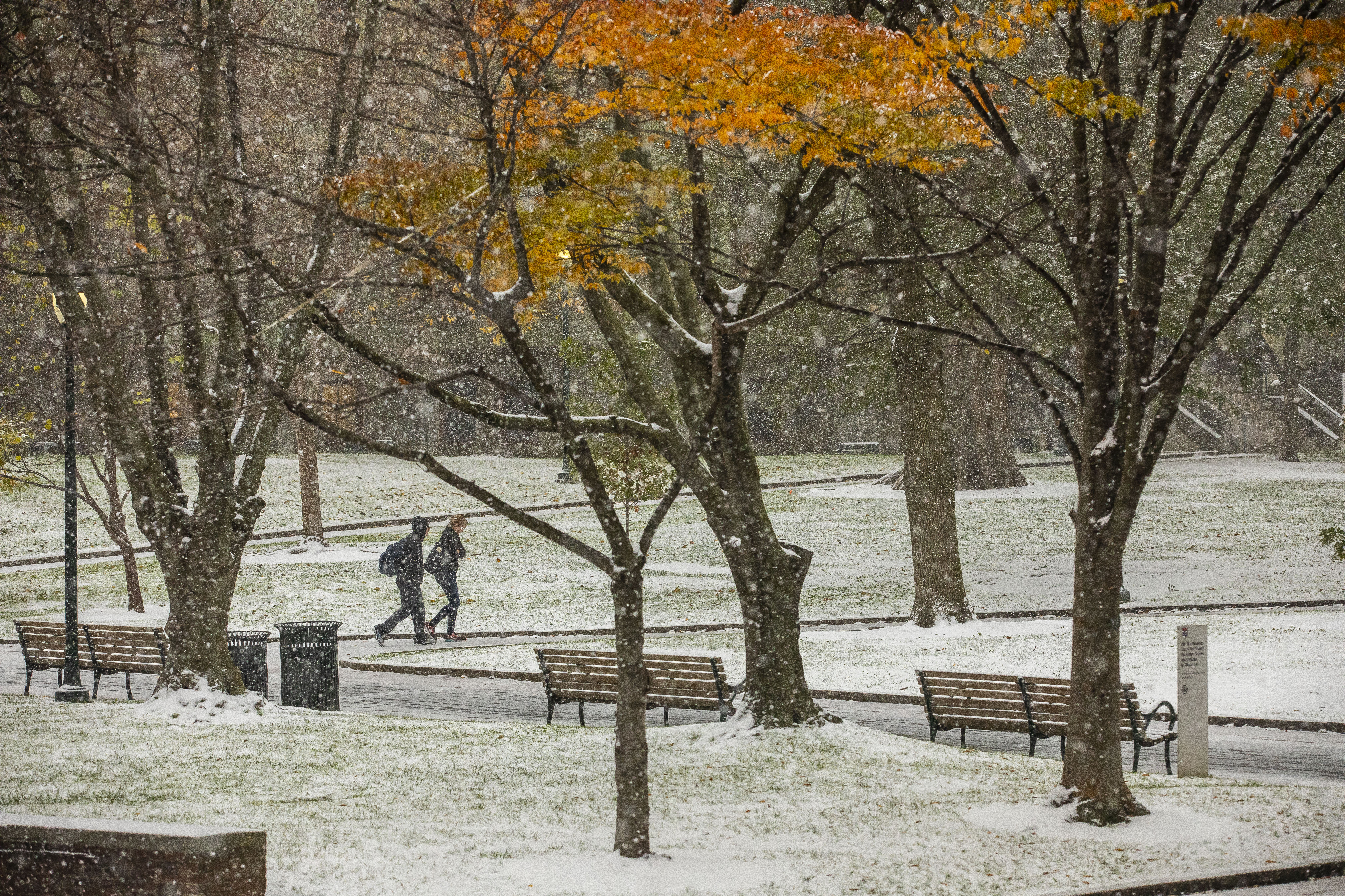 Two student crossing College Green in the snow flurry