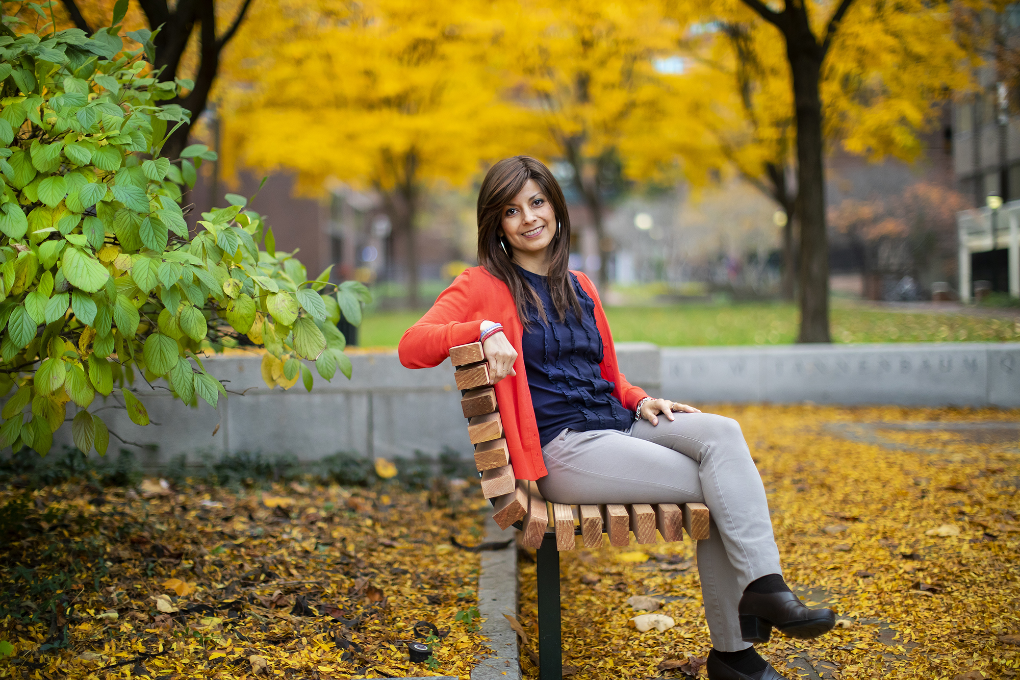 Florian sits on a bench surrounded by yellow fall leaves