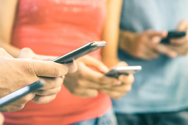 Four people stare at their smartphones.