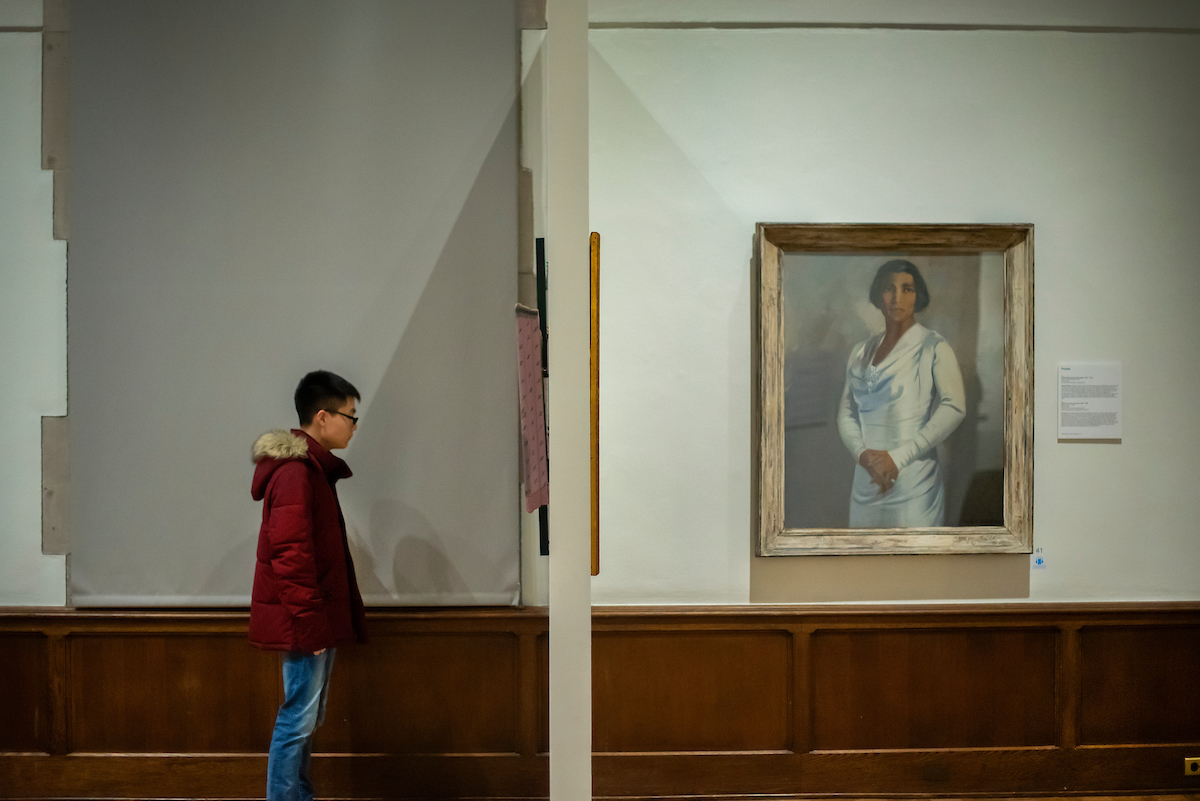 person in profile looking at artwork on wall with portrait of Marian Anderson in full view 