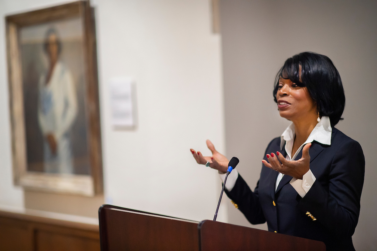 Anita Allen gesturing with her hands while speaking at a podium near a painting of singer Marian Anderson