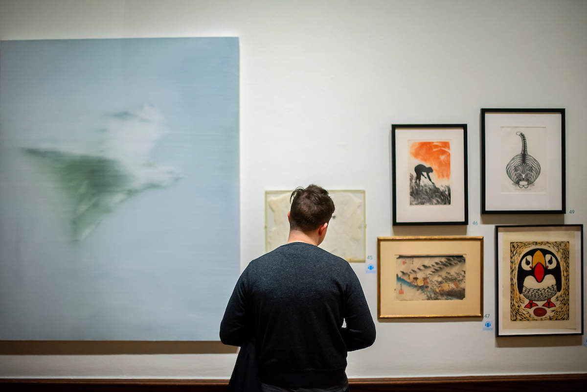 person looking at wall of six artworks