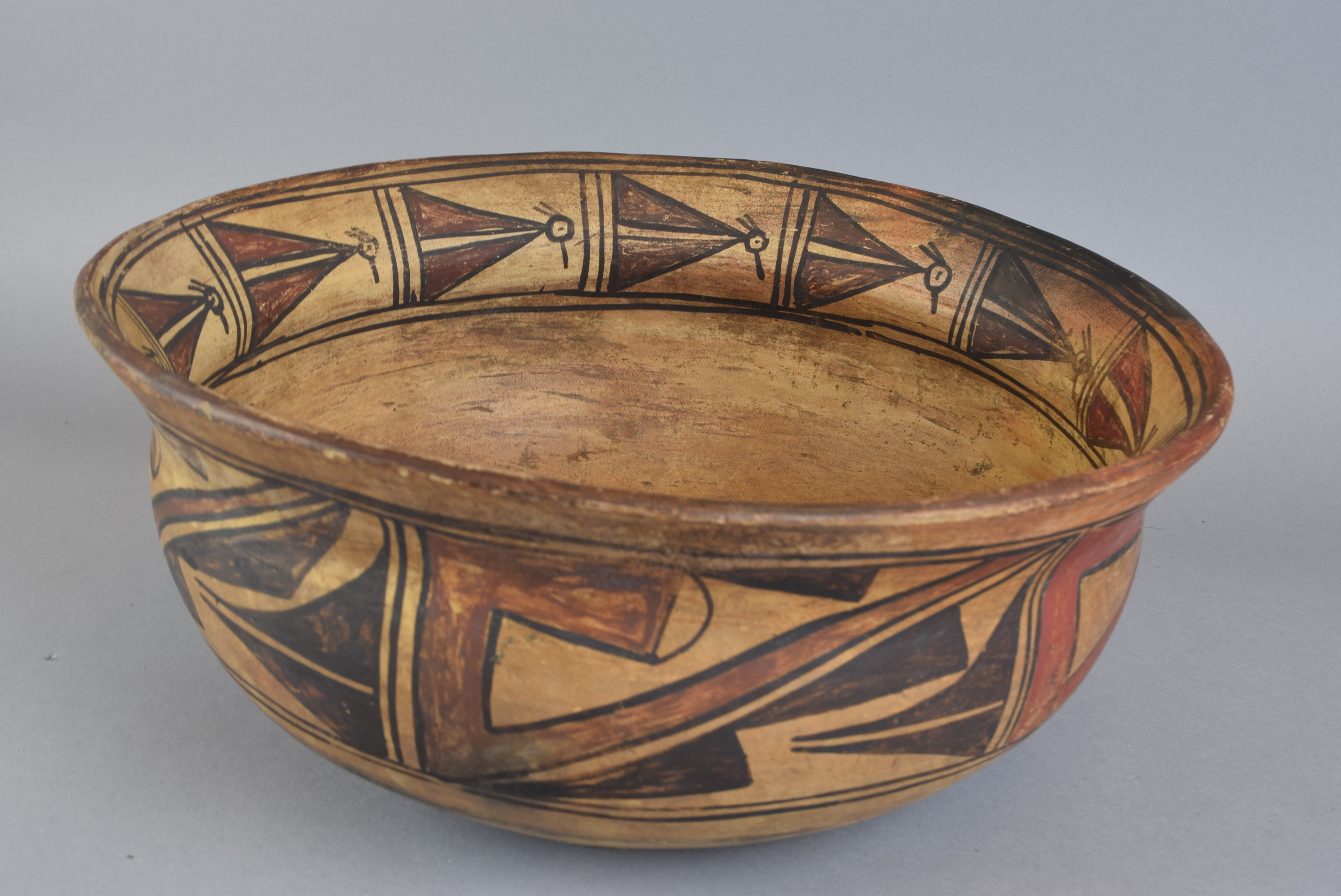 A bowl with brown and beige figures on the rim