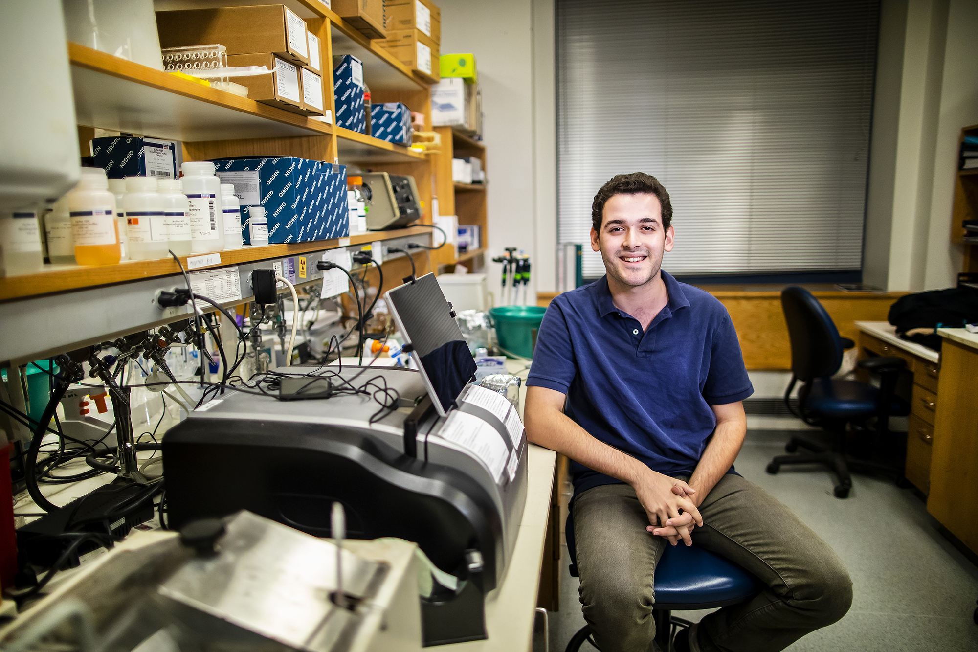 Penn senior Andrew Ravaschiere seated in a lab surrounded by equipment
