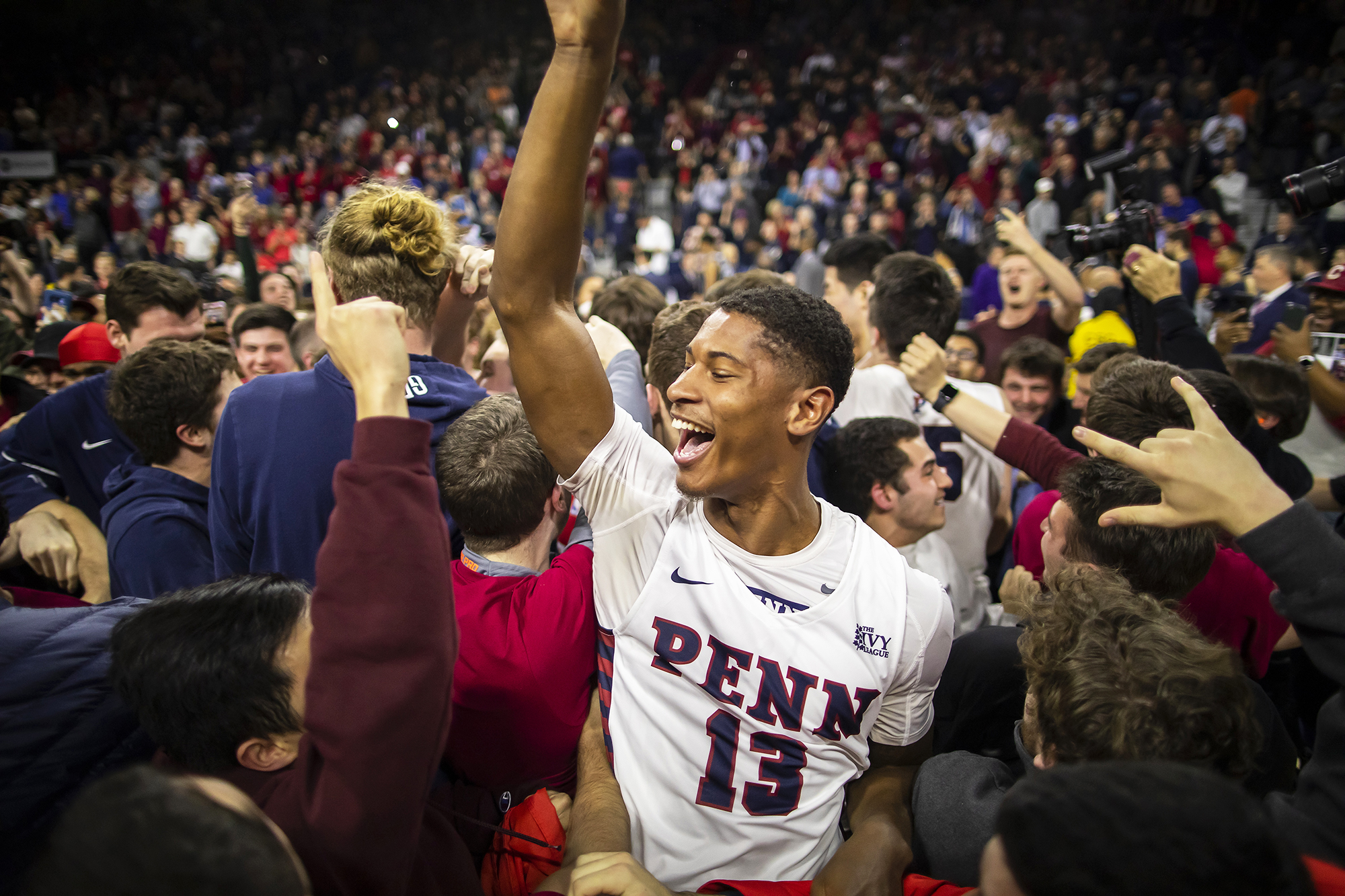 Penn basketball players and fans celebrate on the court after beating Villanova