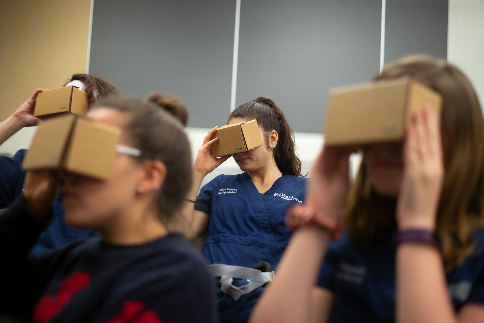 Students holding up cardboard virtual reality reader devices. 