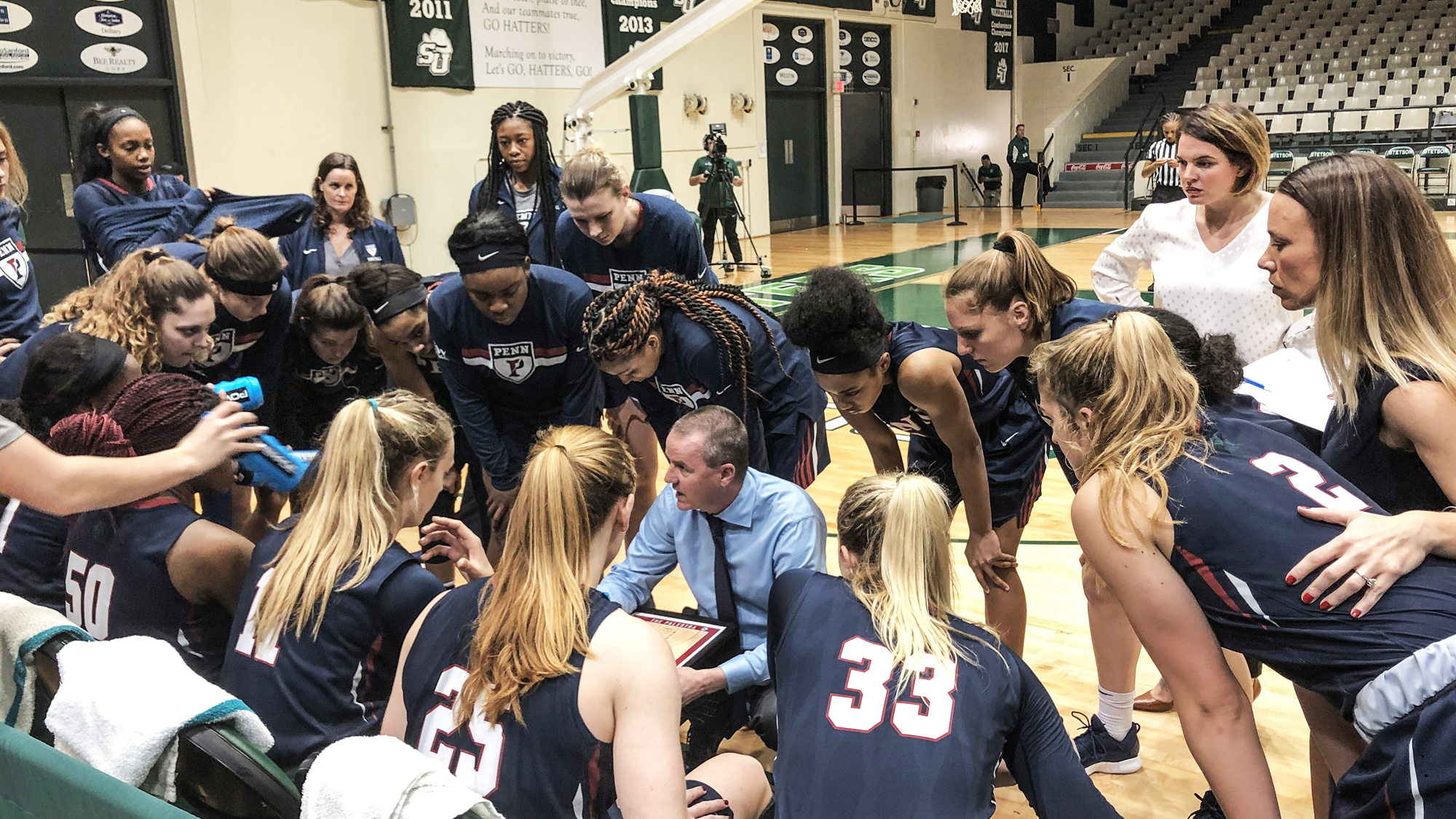 The women's basketball team and coach huddle on the sidelines during a game against Stetson