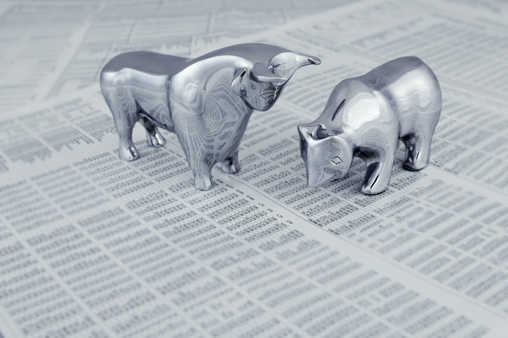 silver bull and bear figurines on top of a newspaper stock market section
