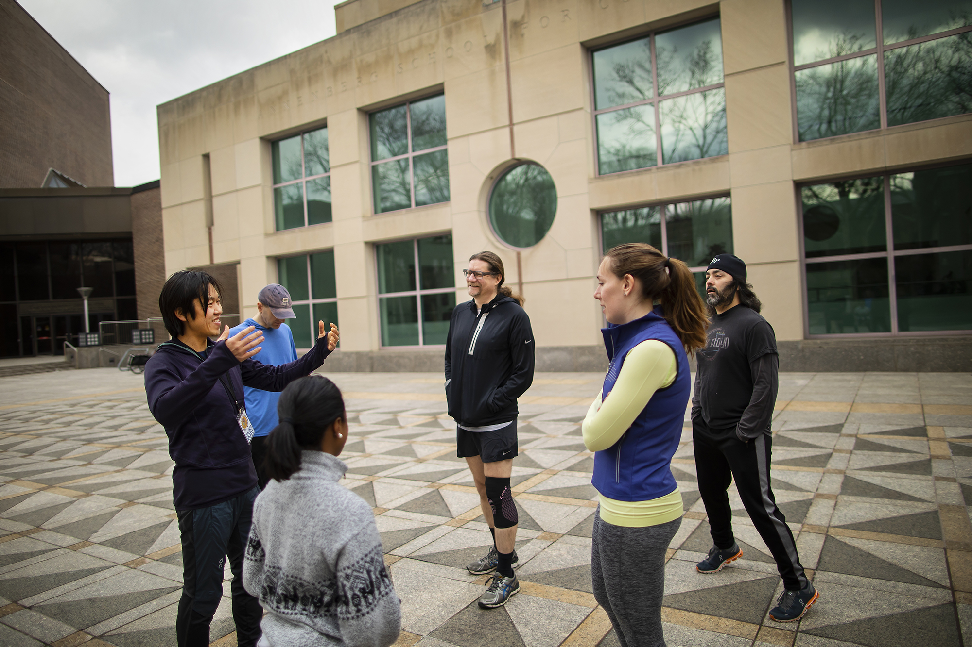 A group in exercise clothing talks in an outside plaza area.