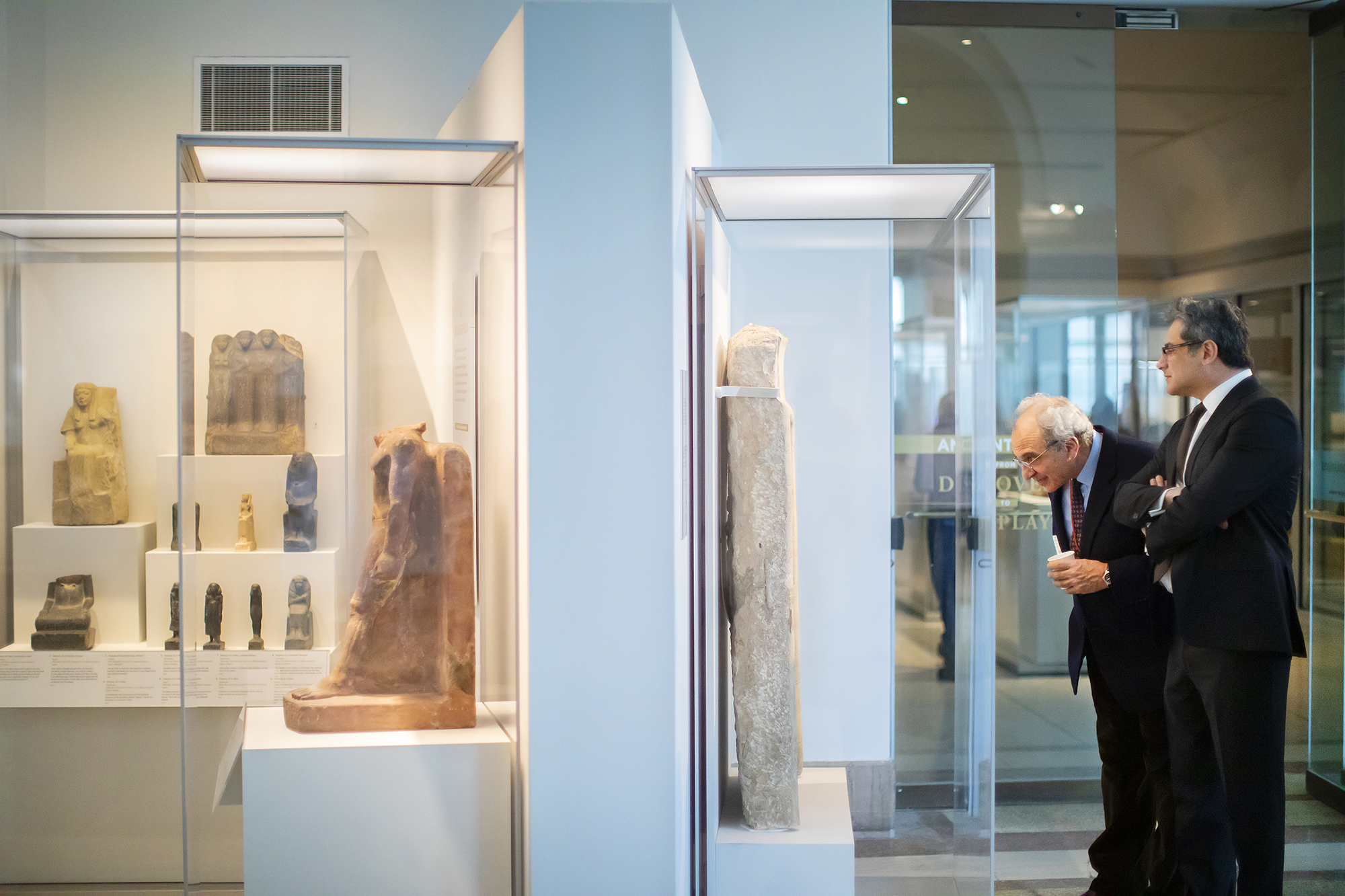 Two men looking into a display case with Egyptian artifacts. 