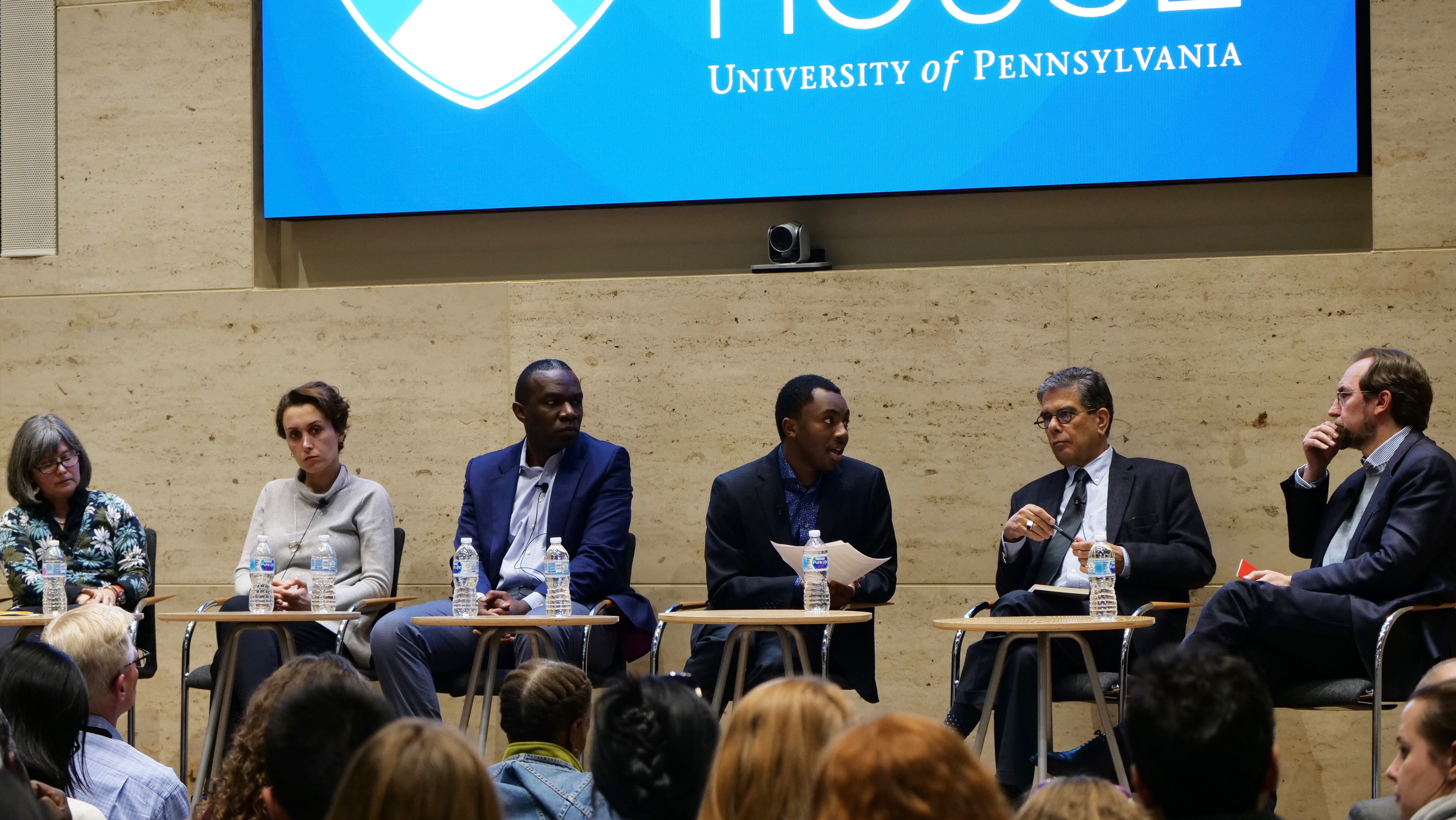 Six people sitting on a stage during discussion.