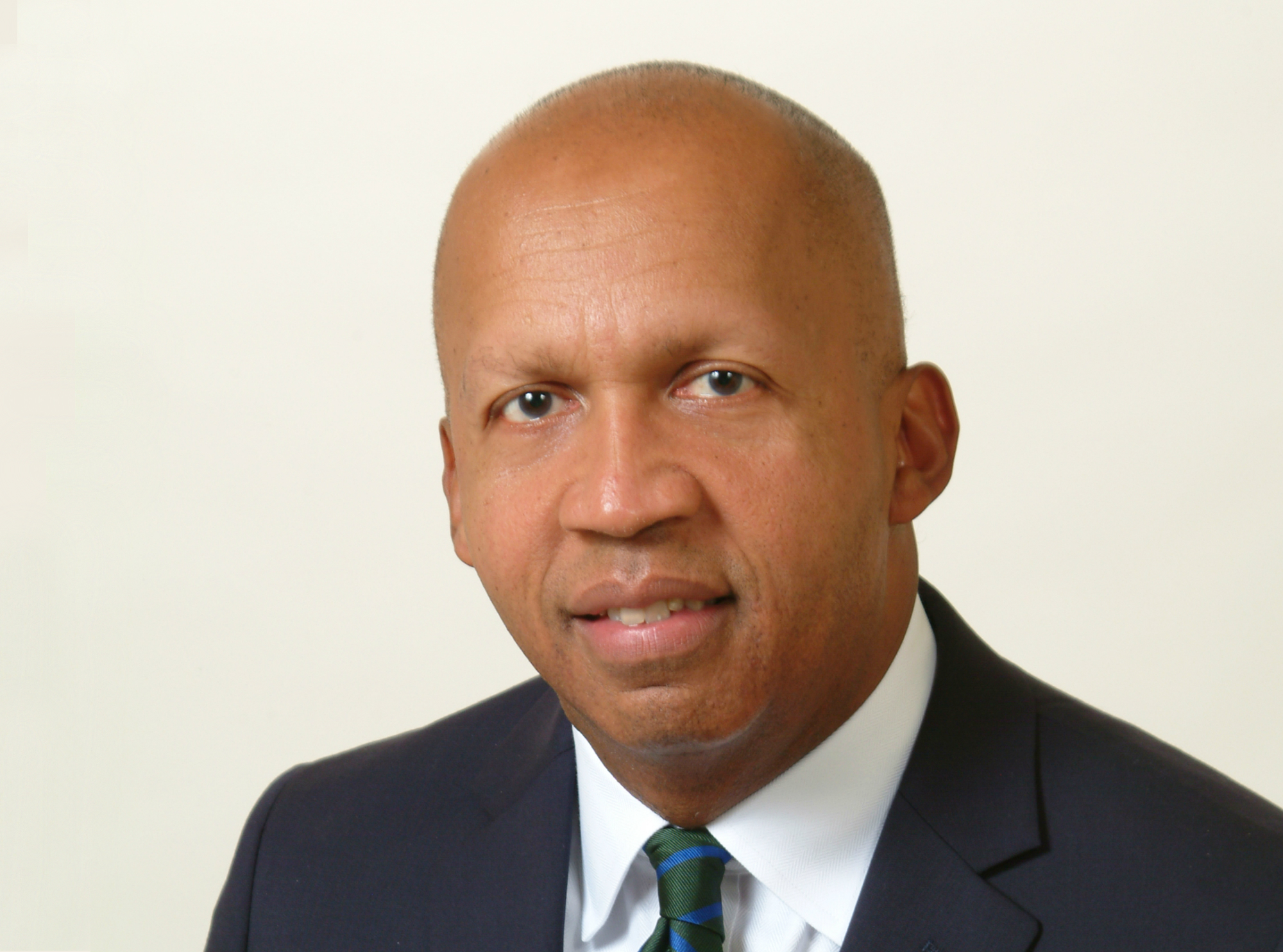 Bryan Stevenson wearing a black suit and green and blue striped tie.