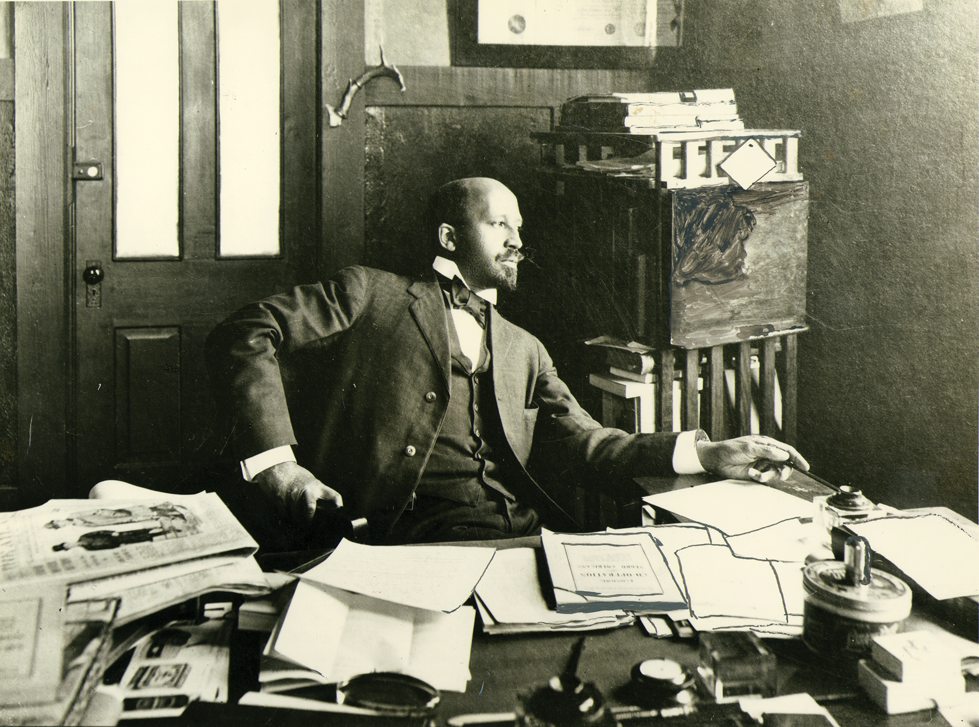 W.E.B. Du Bois sits at his desk in his office.