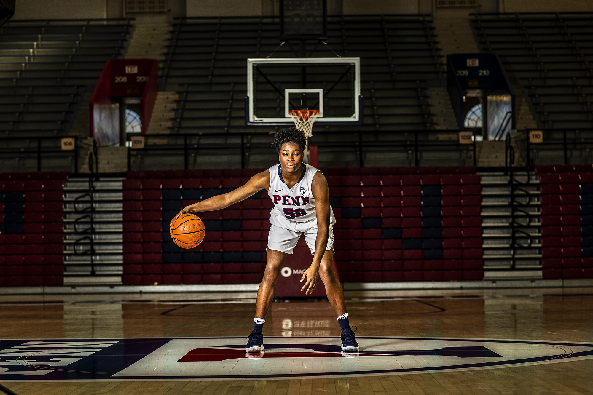 Princess Aghayere dribbles a ball on the Penn logo at the Palestra.