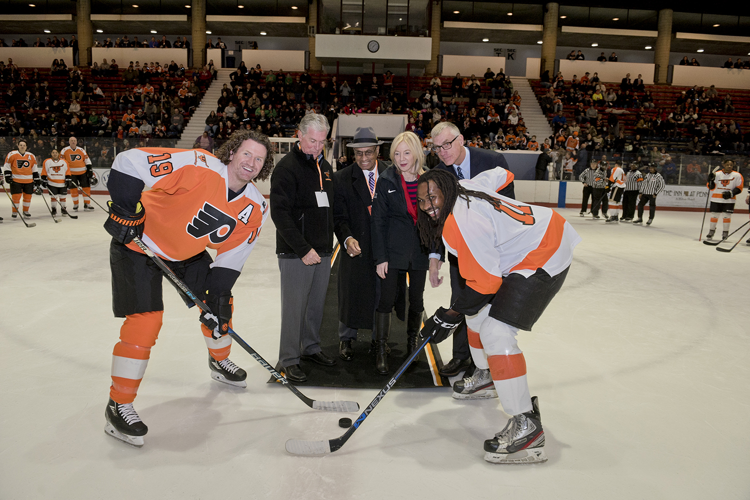A Flyers alum and a Snider Hockey player pose for a ceremonial puck drop with Dr. Gutmann, Willie O'Ree and Bill Whitmore