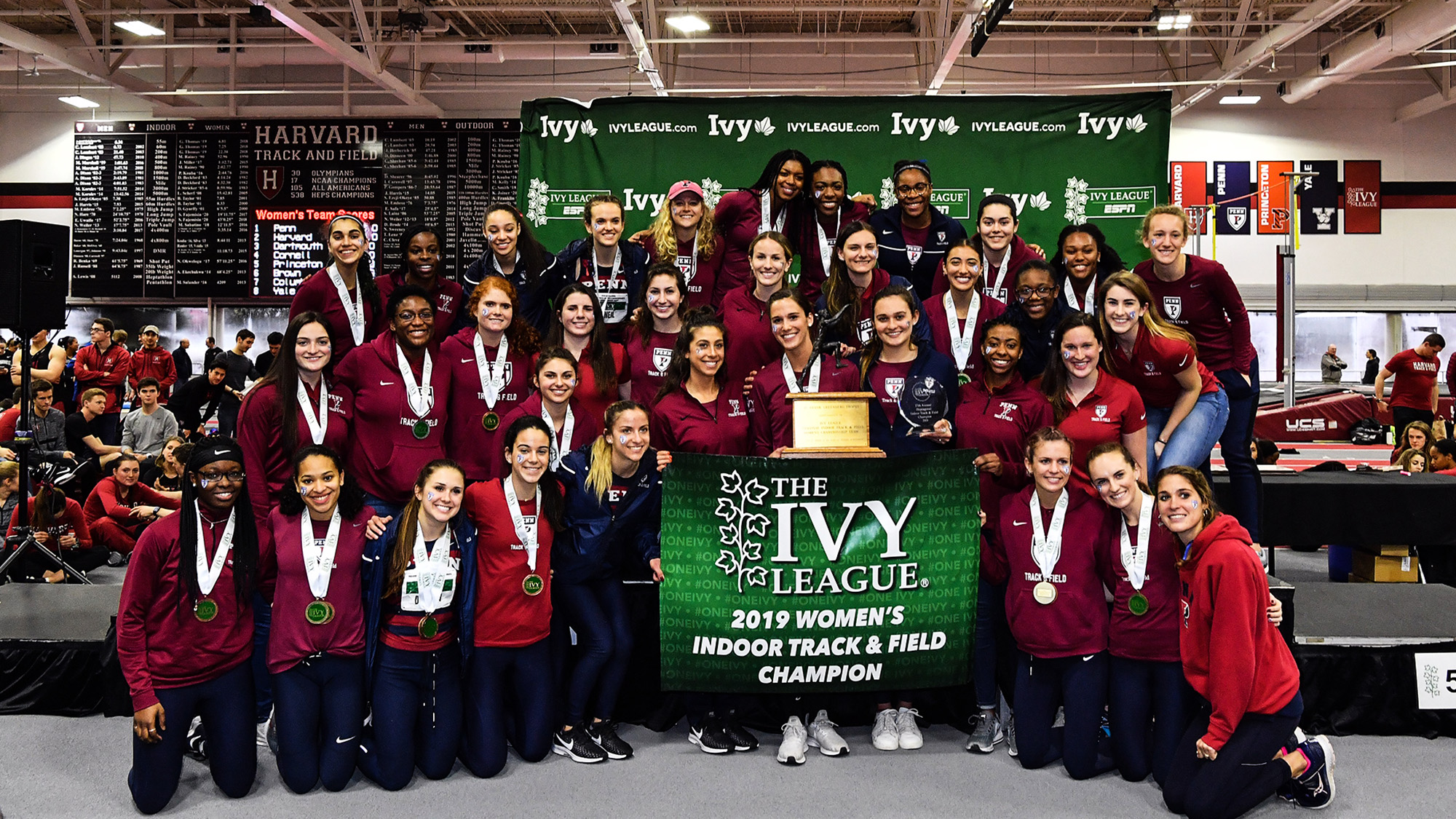 Members of the women's track and field team pose with the Heps indoor championship banner.