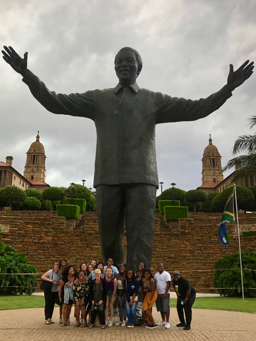 Students and professor gathered in front of a giant statue of Nelson Manela. 
