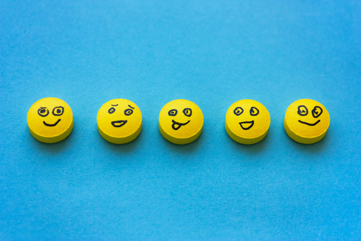Five round pills lined up with smiley faces drawn on the front