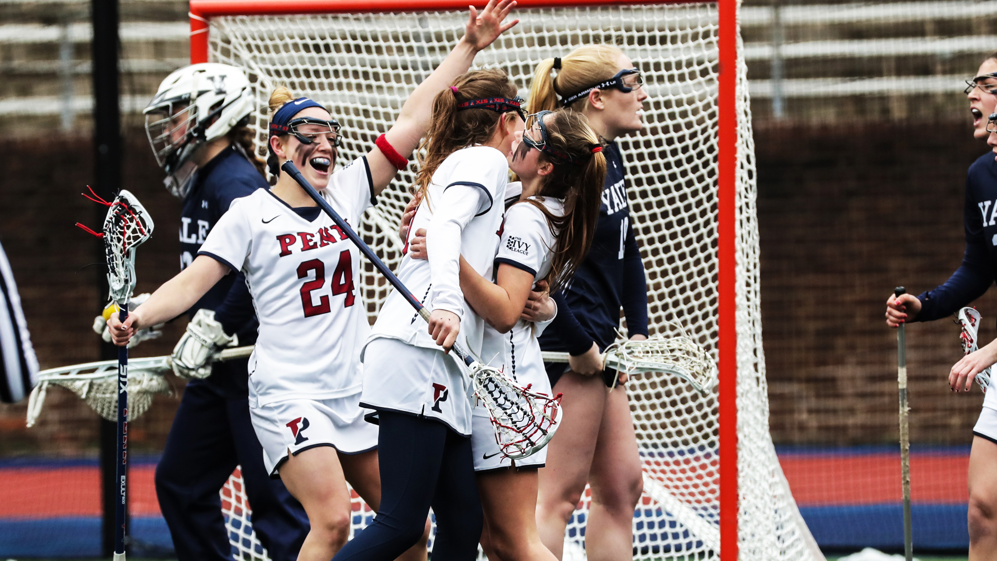 Penn women's lacrosse players celebrate after scoring a goal.