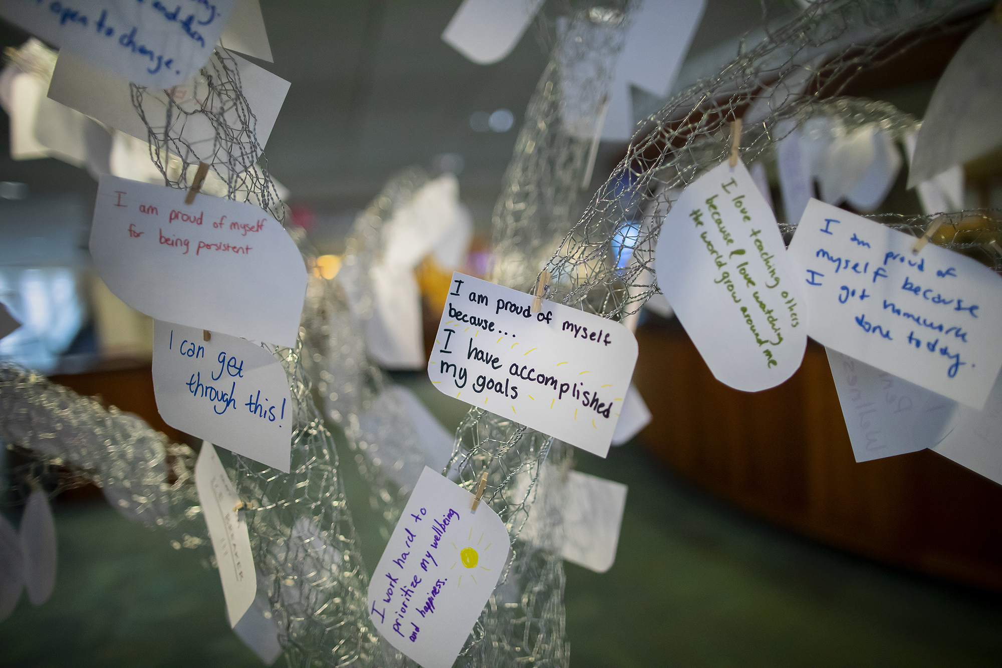 A variety of affirmation notecards hang from the tree sculpture