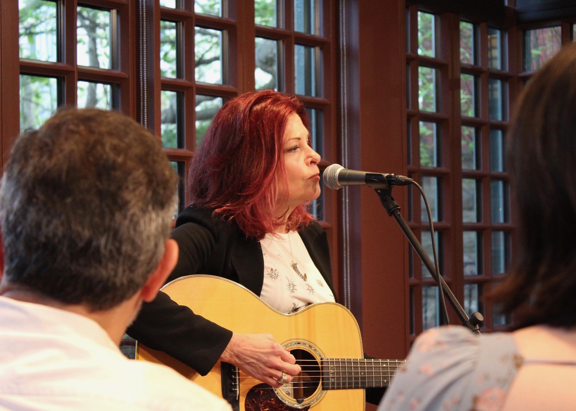 Rosanne Cash playing the guitar and singing into a microphone. 
