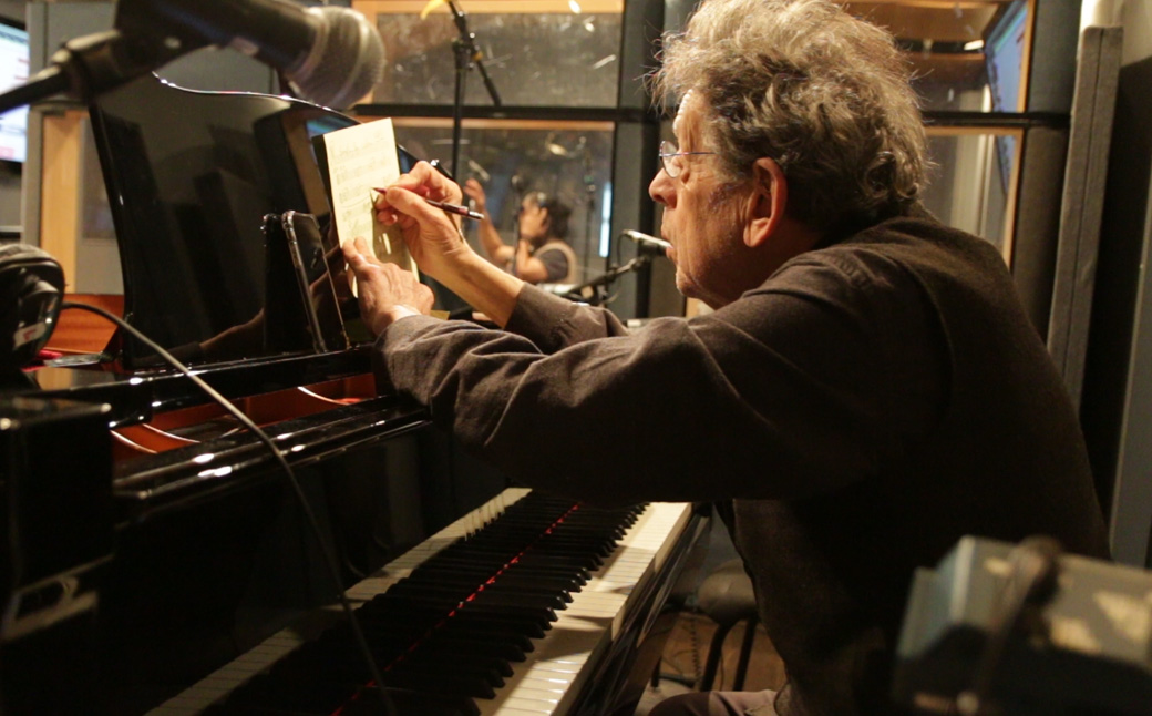 Philip Glass writing at piano