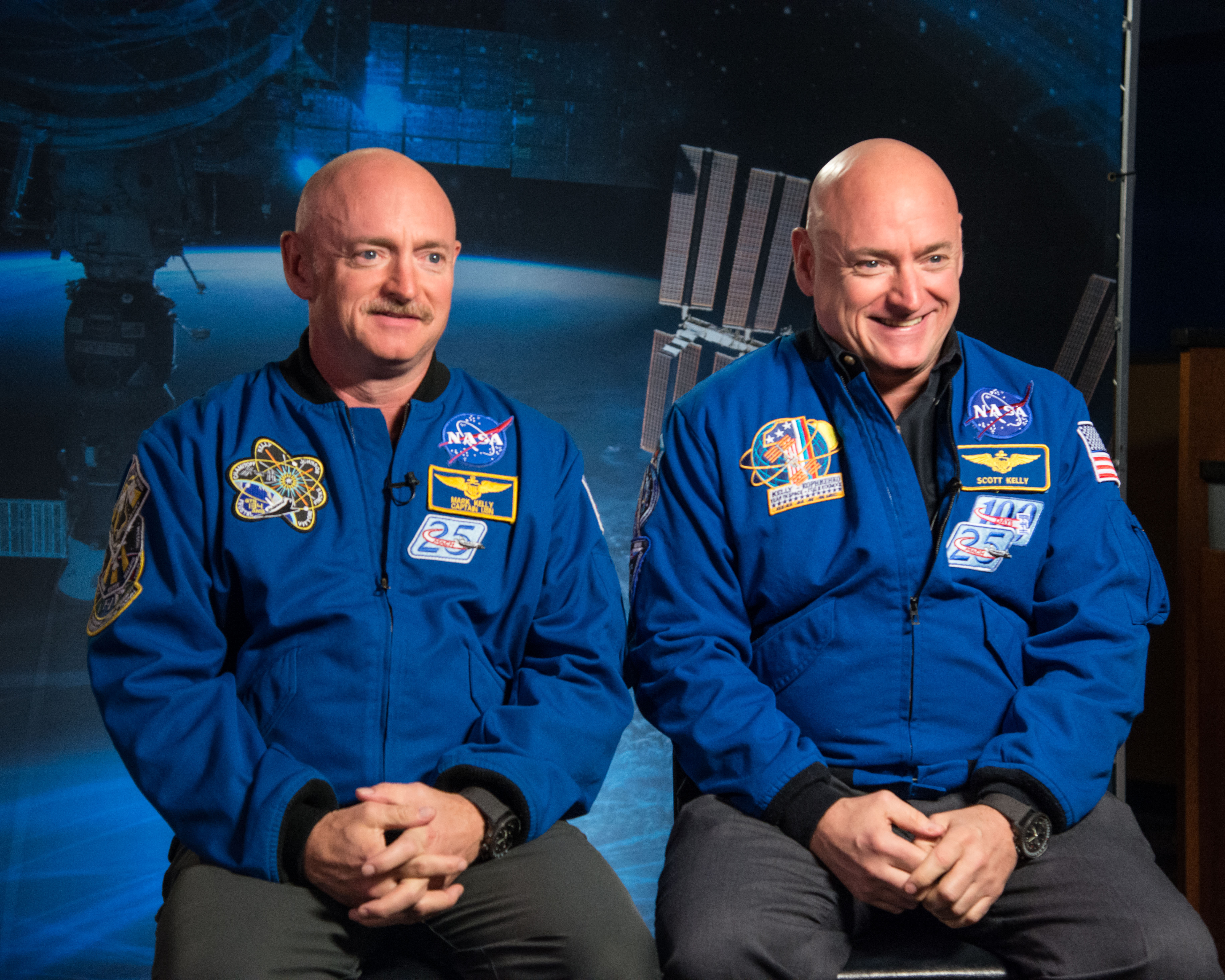 Two bald men in NASA gear. The one on the left has a mustache. 