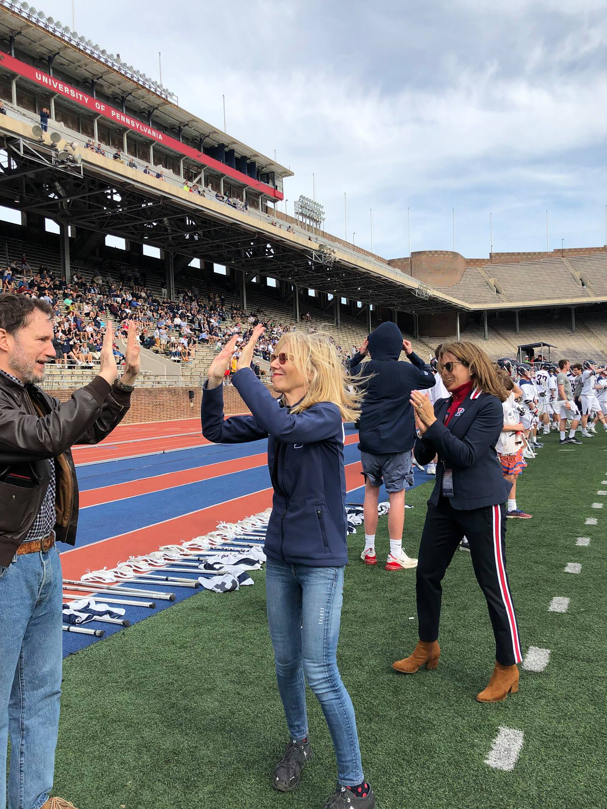 Penn President Amy Gutmann high-fives with her husband while AD Calhoun looks on.