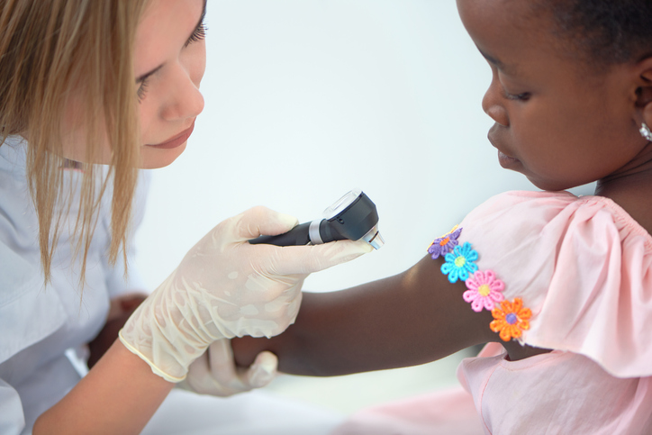 doctor with a gloved hand examines young child's arm during a skin test screening