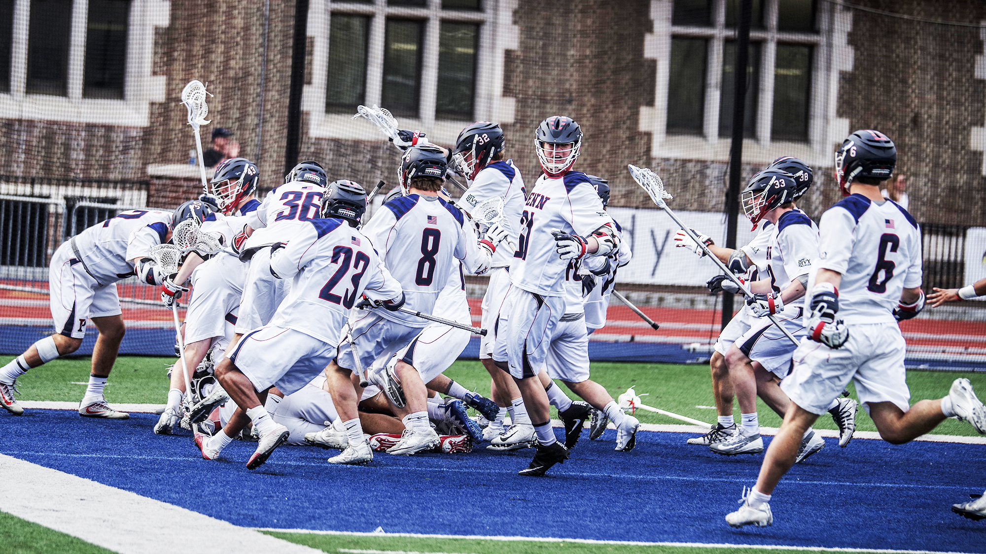 Members of the men's lacrosse team celebrate in a group.