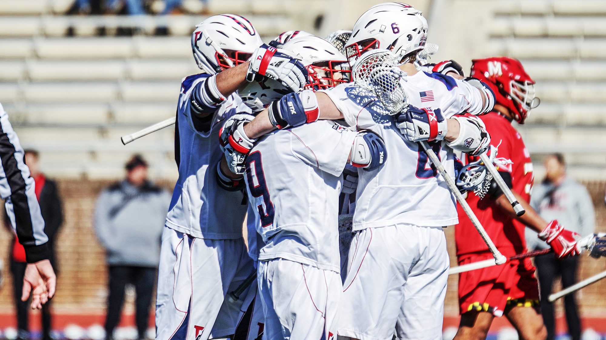 Men's lacrosse players celebrate in a circle.