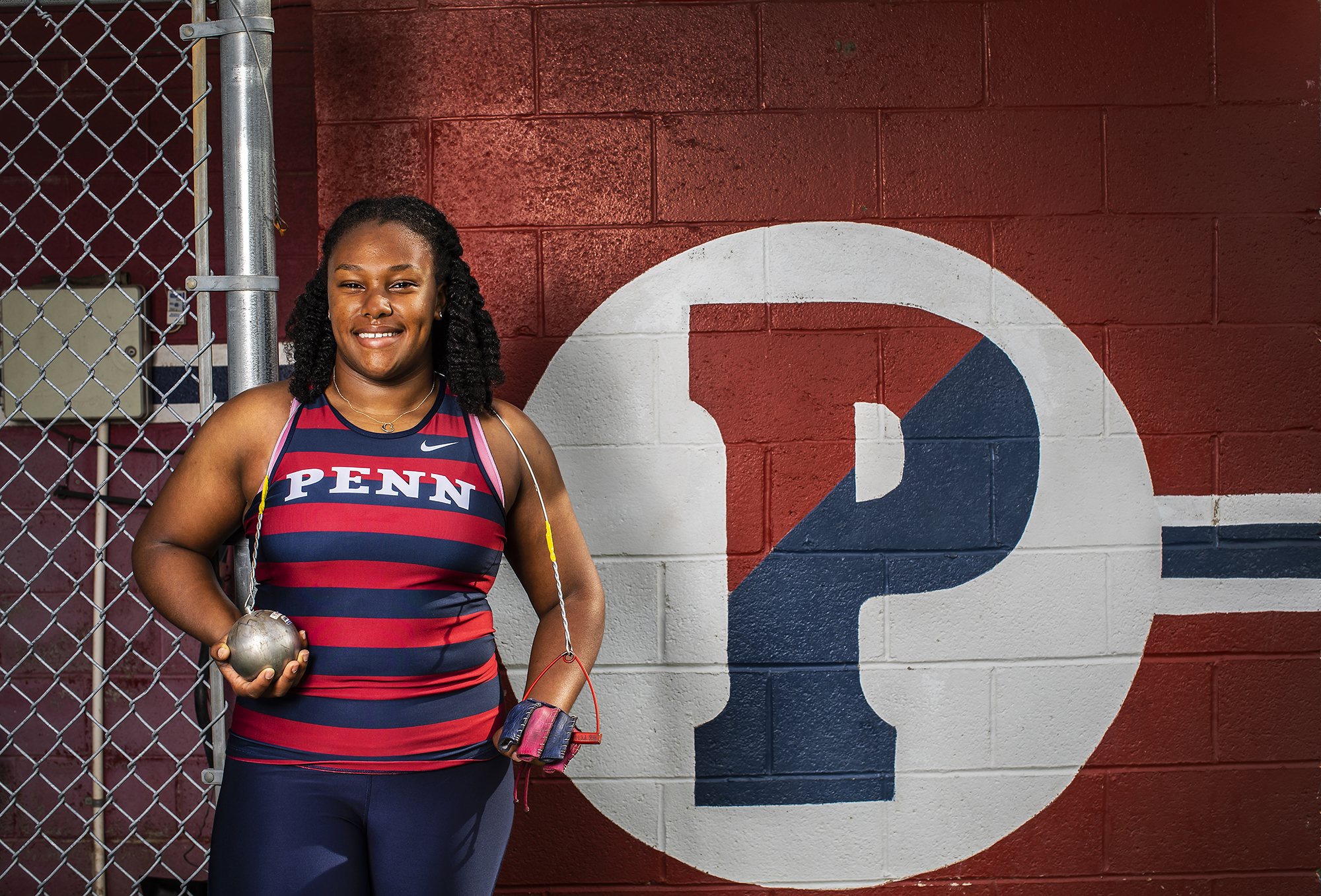 Rachel Lee Wilson poses with a hammer ball next to a Penn P painted on the wall.