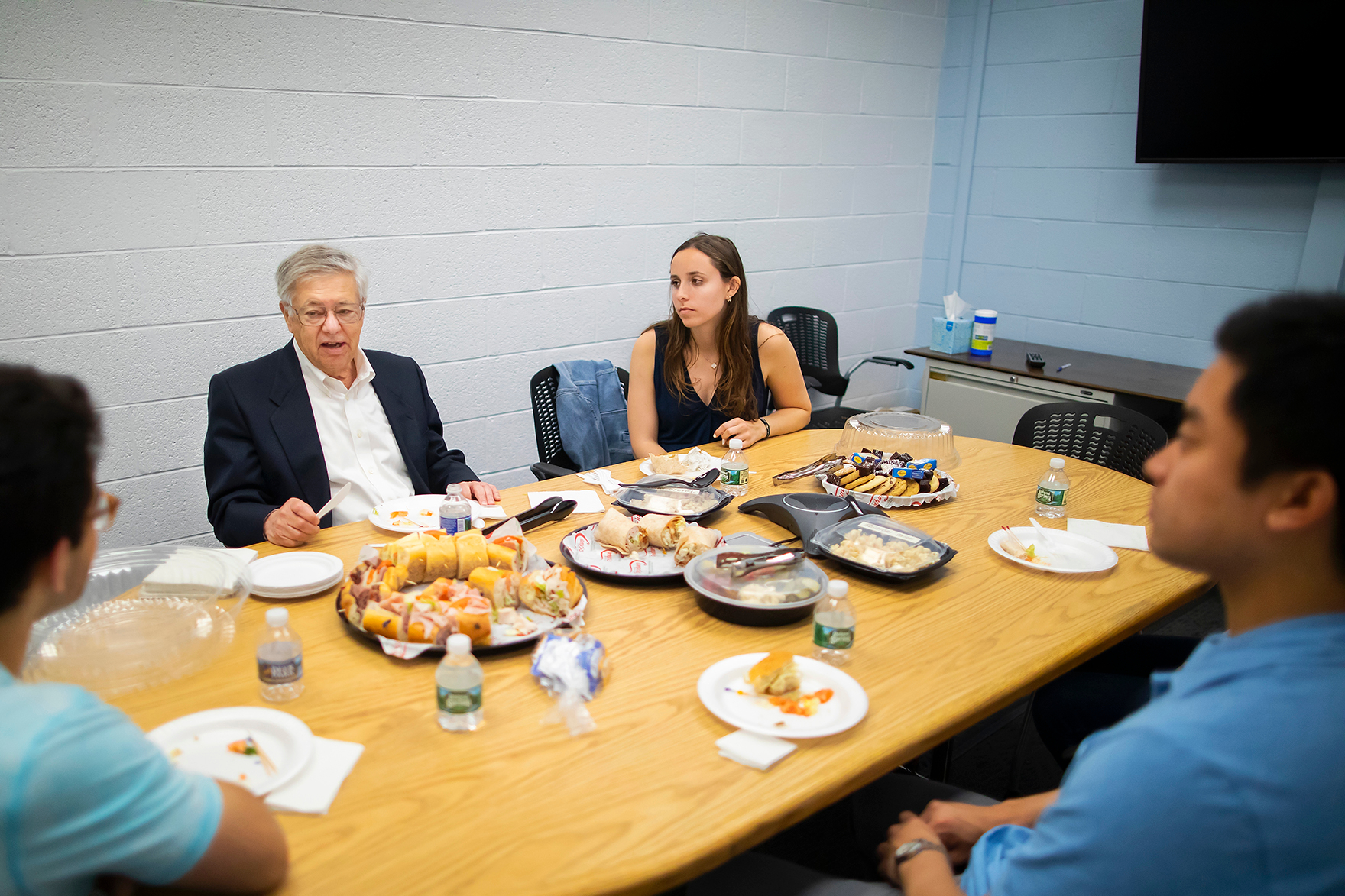 students sitting around a table over lunch talking to a professor