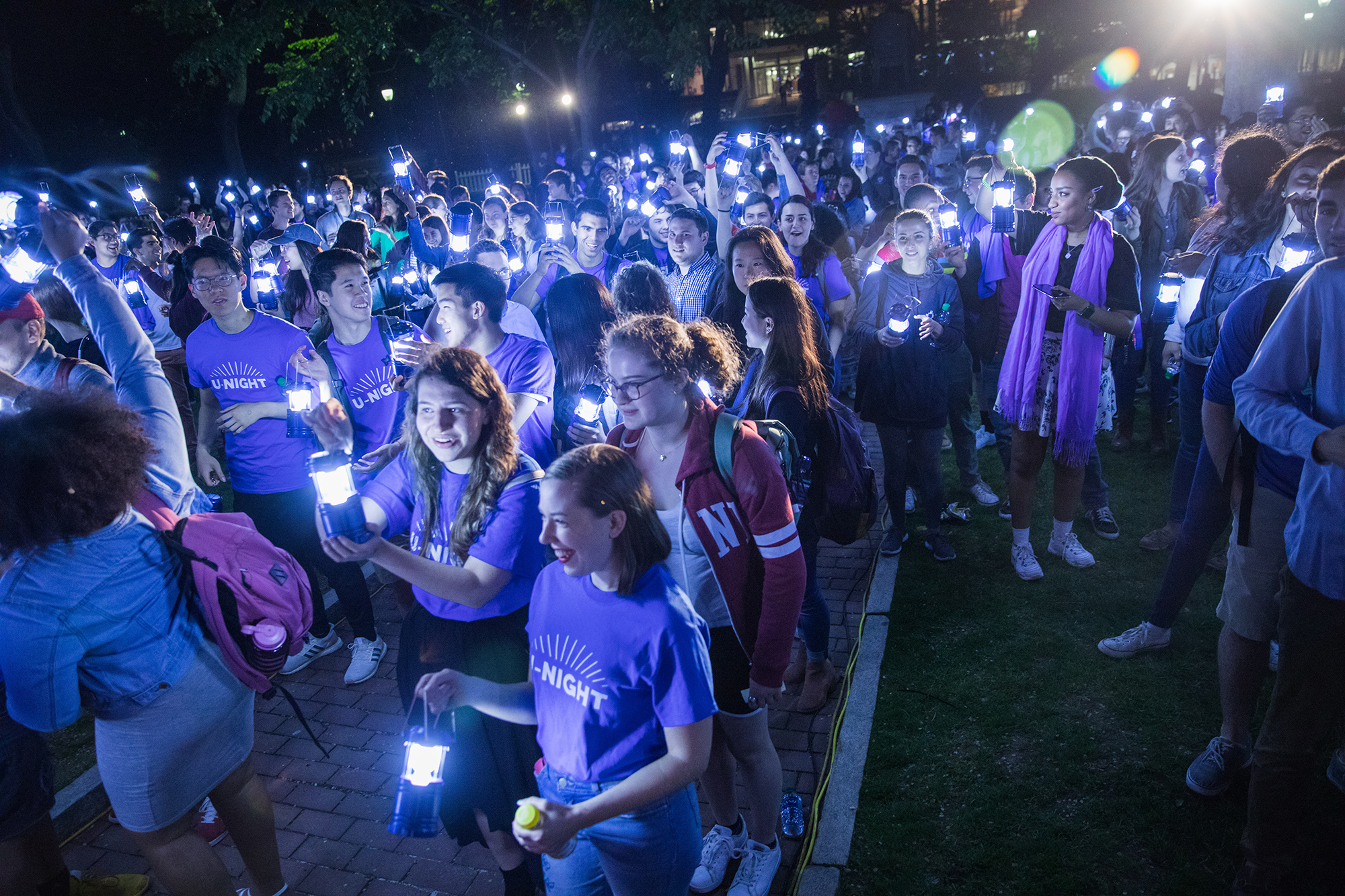 A nighttime, outdoor gathering of a group of students holding small lanterns at U-Night