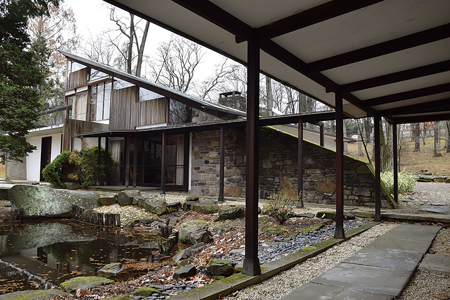 George Nakashima’s Arts Building, the facade of the house with a portico and a small pond surrounded by stones.