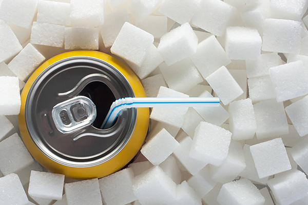 soda can with straw surrounded by a pile of sugar cubes